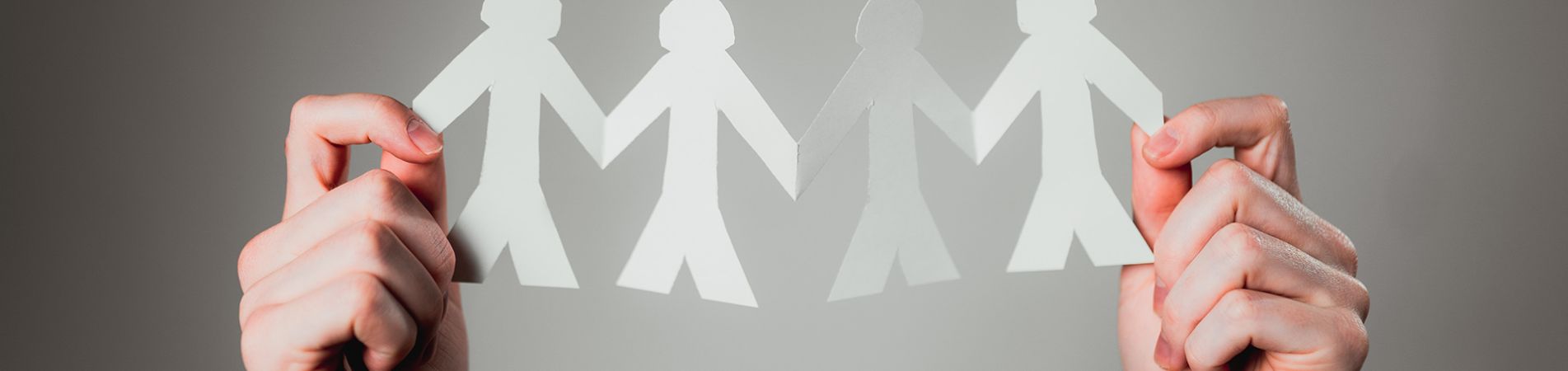 Zwei Hände halten eine Papierkette mit Figuren in die Höhe
