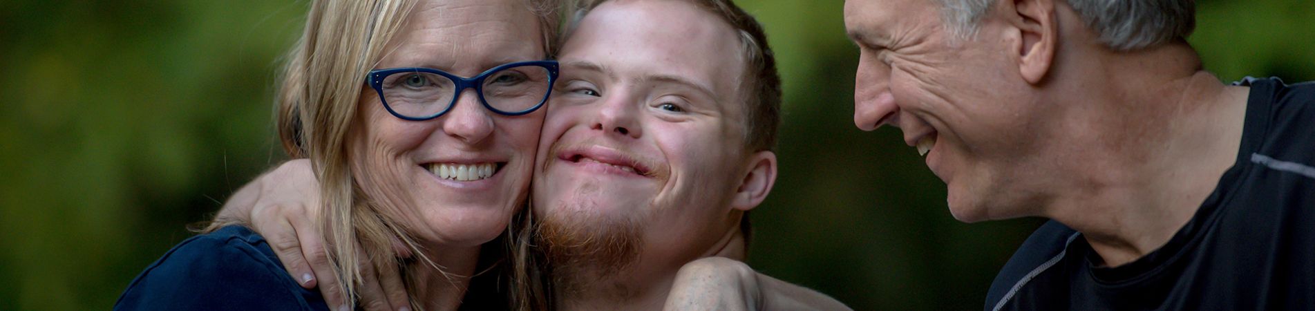 Mutter umarmt ihren Sohn. Der Vater lächelt die beiden an.